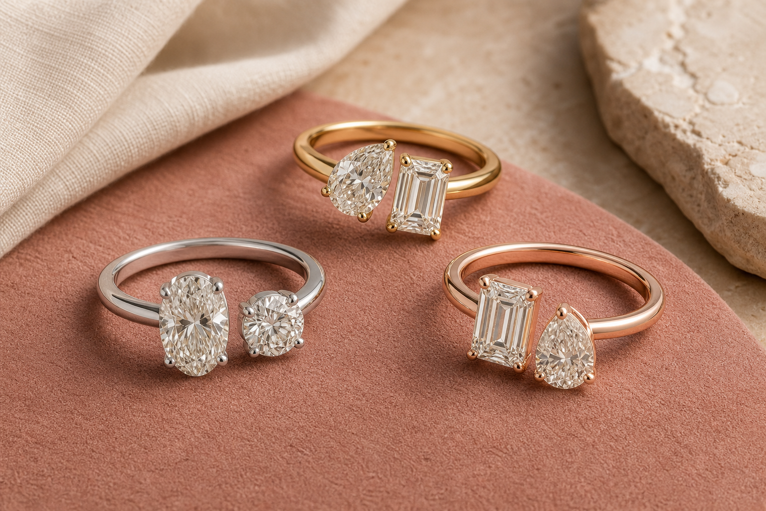 Three two-stone diamond rings showing pear, emerald, oval and round cut combinations in different metal tones