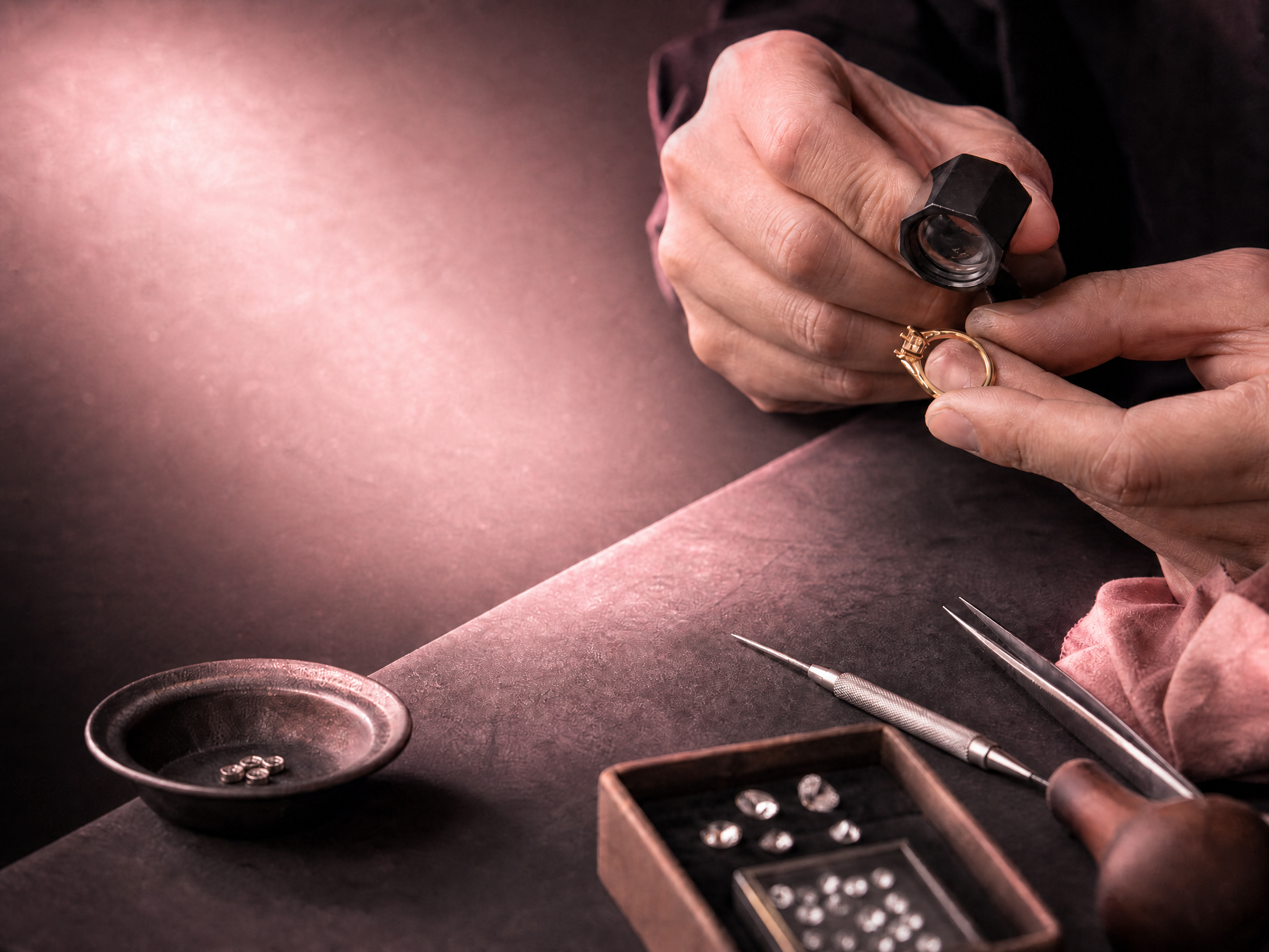 Jewelry artisan inspecting a Lia Fáil Toi et Moi ring setting with a loupe